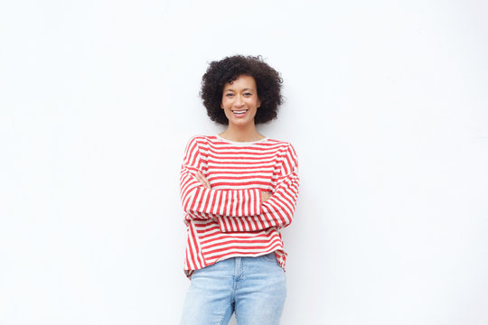 happy african american woman smiling with arms crossed against white wall