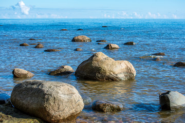 rock covered beach in countryside in Latvia, large rocks in water