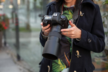 Close-up of professional female photographer on the street photographing on a camera.