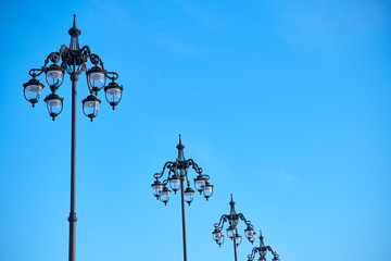 Fototapeta na wymiar Wrought streetlamps on the background of blue sky