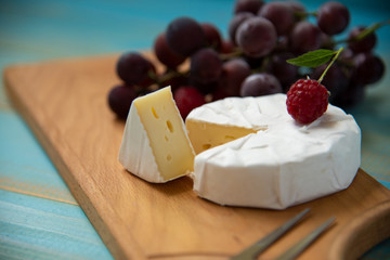 cheese camembert with raspberries and grapes on table