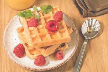 Homemade waffles with berries in plate on a old wooden background/Homemade waffles with raspberry and mint in plate on a old wooden background, top view