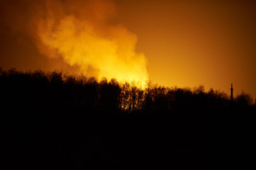 Forest fire with smoke at night, view from the distance