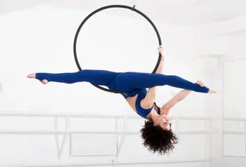 Woman hanging in aerial ring, isolated on white