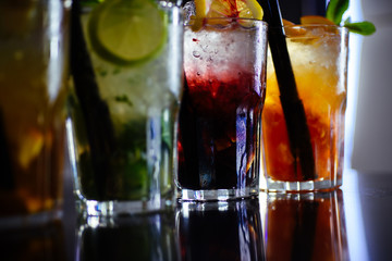 Enjoy a drink. Iced drinks in cocktail glasses in bar. Alcoholic mixed drinks with ice. Juicy beverages with alcohol on counter. Alcohol addiction. Cocktails served in glasses with drinking straws