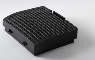 Black lid covering the compartment with a filter at the vacuum cleaner