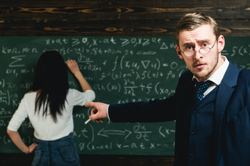 School teacher point finger at student doing sums. School teacher with glasses on smart face