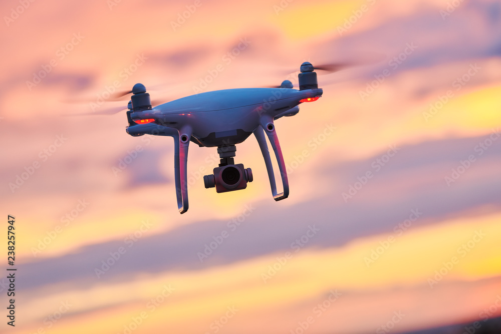 Wall mural drone quadcopter with digital camera flying at sunset