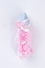 Baby bottle filled with pink pills or sweets.