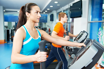 Fototapeta premium Cardio training. Woman and man at cross-trainers in gym