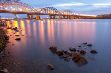 Fototapeta premium Railway bridge over the river. Rosemouth clouds and water.
