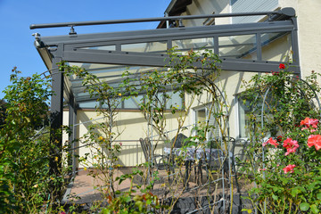 Verglaster Wintergarten mit beschichtetem Metallrahmen, Windmesser und Glasdach, umgeben von...