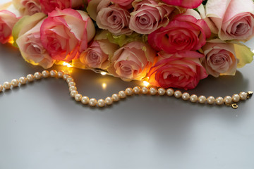 Rose pink flowers bouquet with jewellery on gray table from above, flat lay scene