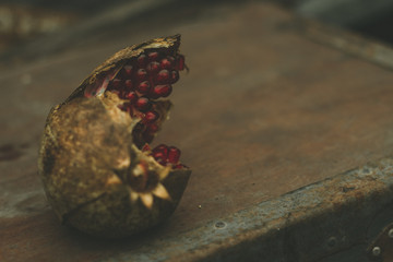 Some red juicy pomegranate, whole and broken, on dark rustic wooden table