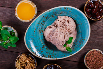 Chocolate ice cream scoops in bowl with mint leaves on wooden background