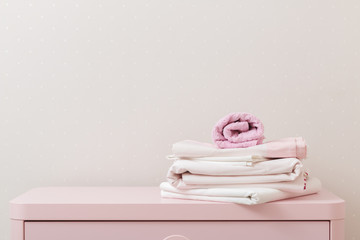 A pile of clean ironed bedding and a towel lies on the dresser.