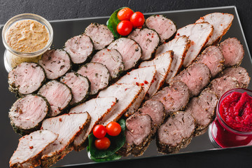 Assorted meat, stuffed chicken roll, meat roll with pepper, greens on black shale background. Meat appetizer, food concept. Top view, flat lay
