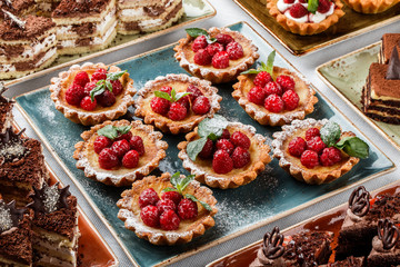 Fruit tart with raspberries and cream, cakes and sweetness on holiday background. Delicious dessert and candy bar.