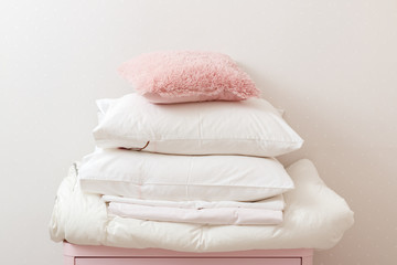 A pile of clean ironed bedding and a towel lies on the dresser.