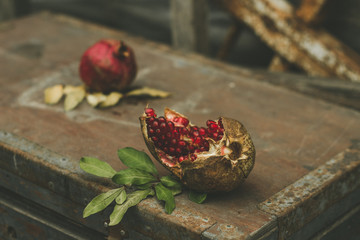 Some red juicy pomegranate, whole and broken, on dark rustic wooden table