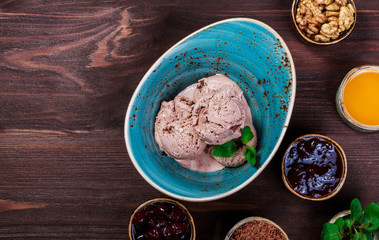 Chocolate ice cream scoops in bowl with mint leaves on wooden background. Top view