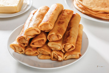 Close-up. Rolls of pancakes with meat are on a white plate