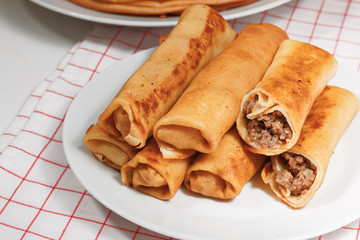 Close-up. Rolls of pancakes with meat are on a white plate