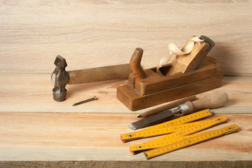 Carpentry concept.Joiner carpenter workplace. Old planer,hammer ,chisel ,meter and pencil on wooden...