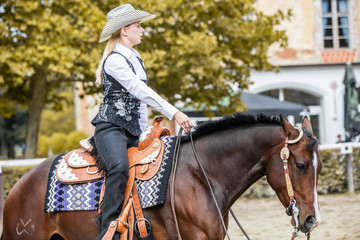 Beautiful cowgirl riding horse with one hand