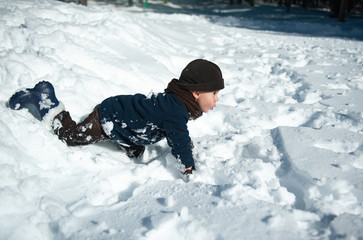 Fototapeta na wymiar Little boy playing in the snow in winter
