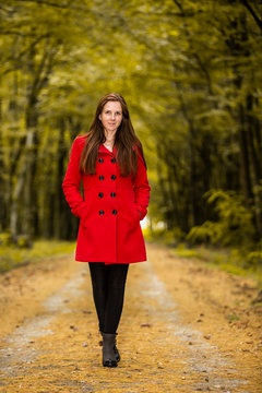 Woman pose with red coat inside the autumn forest