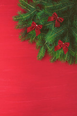 Red Christmas background with green tree bows on wooden background