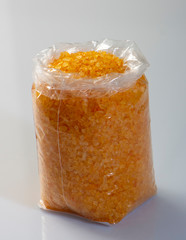 closeup of orange sea salt in plastic bags on the market.