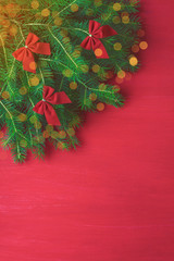 Red Christmas background with green tree bows on wooden background