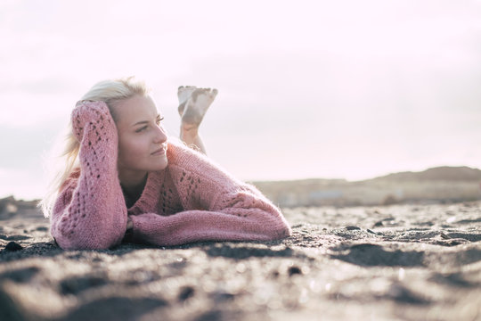 Attractive Lady Lay Down At The Beach On The Sand In Winter Or Autumn Season With A Pink Sweater Enjoying The Outdoor Relaxed Activity Alone With No People Around -millennial Girl Feel The World