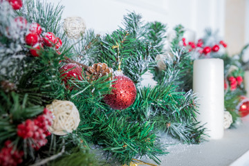 Christmas decoration of holly berry and pine cone.Christmas background. Green branches with red berries. Home decor for holidays. decoration balls with fir cones and fir branches, white candle.