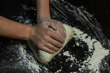 The cook kneads the dough with flour