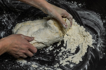 The cook kneads the dough with flour