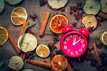 Fototapeta na wymiar Alarm clock and Chrsitmas tea ingredients on jute background