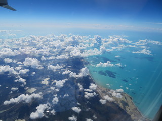 Fototapeta na wymiar Der Blick auf eine wunderschöne Küste der Karibik mit kleinen Wölkchen aus dem Fenster eines Flugzeugs