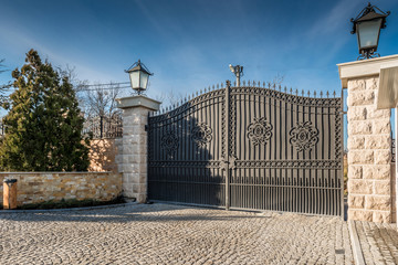 Metal driveway security entrance gates set in brick fence - obrazy, fototapety, plakaty