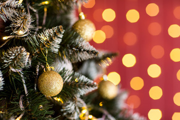 New Year`s green fir-tree, spheres gold, a red background, a wall with small lamps. New Year`s mood.