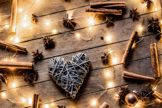 Heart shape decoration and Christmas lights around on wooden background
