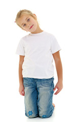 Fototapeta premium A little girl is sitting on the floor in a clean white T-shirt.