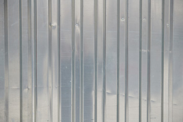 The texture of a piece of silver metal sheet with vertical stripes, background
