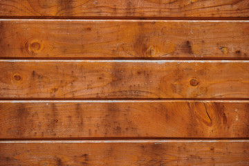 The texture of a wooden wall with horizontal stripes of brown boards, background, close-up