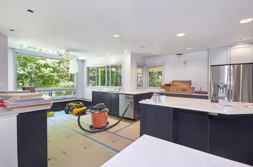 Cabinets and appliances installed – Remodeled kitchen prepared for cooktop and vent installation,...