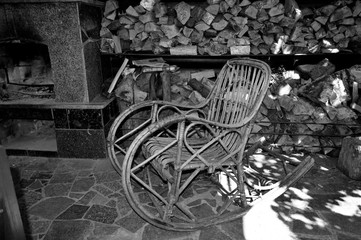 Fototapeta na wymiar Rocking chair stands near the fireplace and firewood