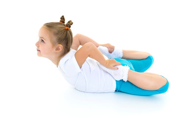 The little gymnast perform an acrobatic element on the floor.
