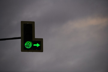 Traffic light with green arrows on the background of cloudy sky